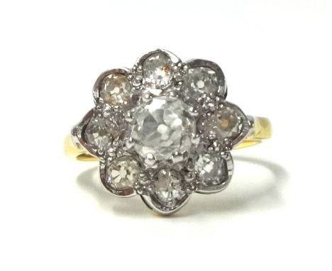 An 18ct gold and diamond cluster ring set with old cut stones, the central claw set stone bordered by smaller collet set ston