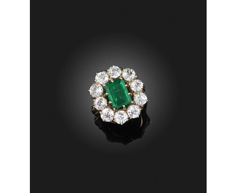An emerald and diamond ring, 19th century, of cluster design, claw-set with a step-cut emerald weighing approximately 2.10 ca