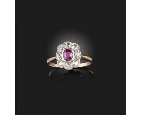 A ruby and diamond ring, early 20th century, of cluster design, set with an oval ruby within a border of cushion-shaped diamo