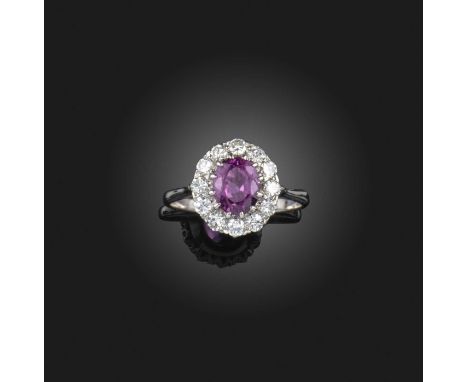 A ruby and diamond ring, of cluster design, set with an oval ruby within a border of brilliant-cut diamonds, mounted in white