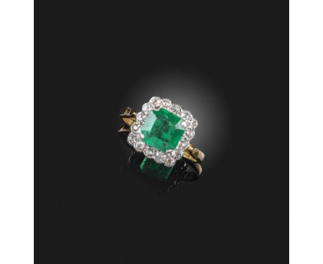 An emerald and diamond cluster ring, set with a step-cut emerald within a surround of diamonds, mounted in platinum and gold,