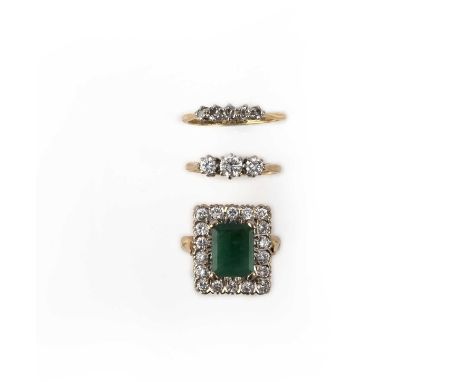 A collection of three rings, comprising: a ring of cluster design, set with a step-cut emerald within a border of brilliant-c