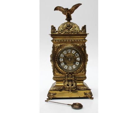 A brass cased mantle clock with an eagle finial and dial enamelled with Arabic numerals, to an 8-day striking movement enclos