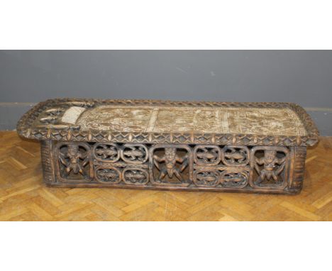 An important carved African Bamileke bed profusely carved from a single trunk. The resting position carved with a seated &lsq