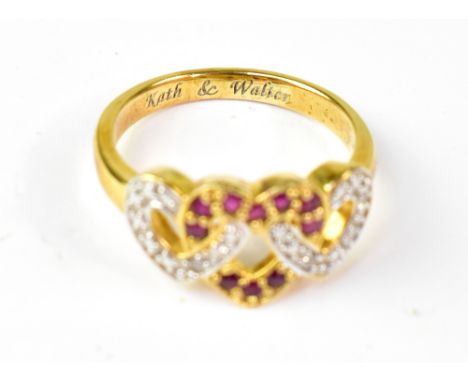 A gold plated dress ring with triple heart set with small white and red stones, size O. CONDITION REPORT: The ring is gold pl