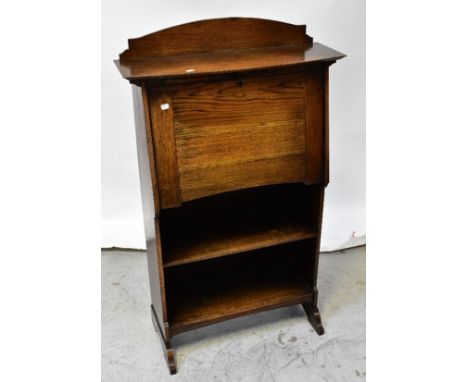 An early 20th century oak student bureau, the arched raised back above bow front top and fall front with an assortment of pig