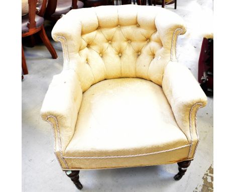 A Victorian walnut framed low button pressed tub chair, with scrolling arms and turned front legs, to brass caps and castors.