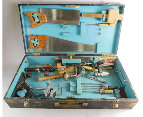 An ebonised wooden tool chest, containing a number of tools, metal planes, saws, drills, etc.