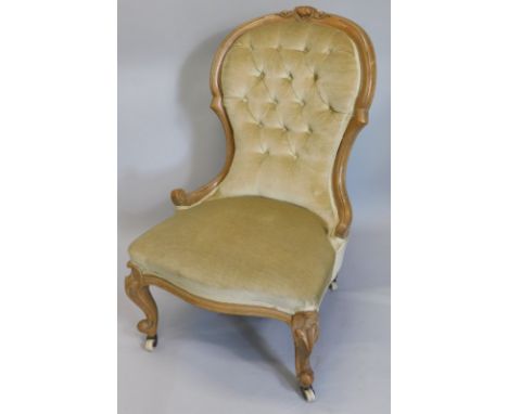 A Victorian walnut spoon back nursing chair, with a button back, padded seat on cabriole legs with ceramic castors.