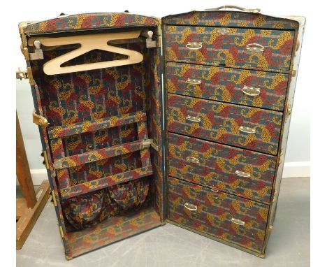 An early 20thC canvas and brass bound wardrobe trunk, with various luggage labels.