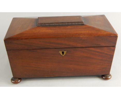 A mid 19th mahogany sarcophagus shaped tea caddy, the part gadrooned lid hinging to reveal an open centre flanked by compartm