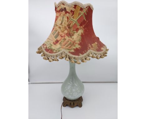 A Chinese Celadon floral design table lamp sat upon a gilt metal base. Comes with a Chinese silk design shade. [70cm in heigh