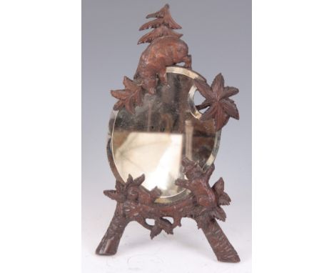 A LATE 19TH CENTURY BLACK FOREST EASEL MIRROR of oval shape, having two bears playing next to a squirrel amongst pine leaves 