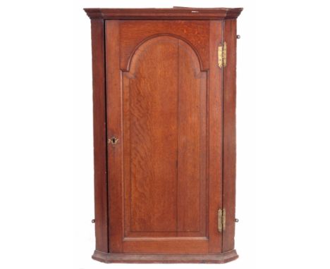 AN EARLY 18TH CENTURY OAK HANGING CORNER CUPBOARD with arched fielded panelled door, the interior has an unusual original por