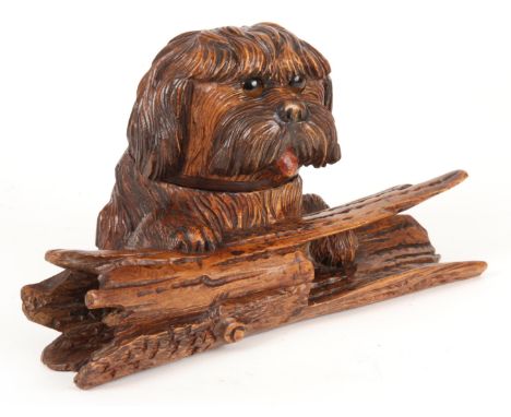 A LATE 19TH CENTURY CARVED BLACK FOREST INKWELL AND PEN HOLDER FORMED AS A DOG RESTING ON A LOG finely carved with coloured g