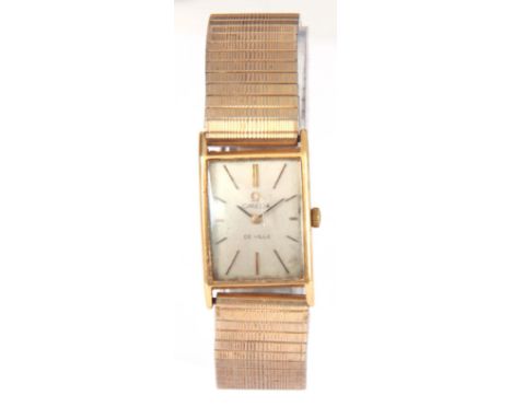 A VINTAGE 18K GOLD OMEGA DEVILLE WRIST WATCH on gold plated and steel bracelet, the rectangular gold case enclosing a silvere