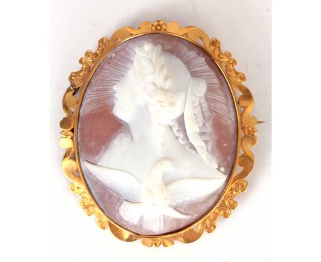 A 19TH CENTURY OVAL CARVED CAMEO BROOCH depicting a bust portrait of a young lady with winged dove above - in gold metal fram