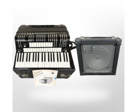 A Hohner Electravox De Luxe piano accordion with instructions, in travel case, together with a Roland Cube 15 amplifier with 