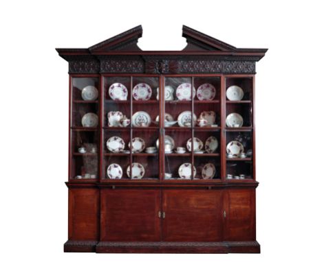 A GEORGE II MAHOGANY BREAK-FRONT LIBRARY BOOKCASE in the manner of William Kent, circa 1735, the upper part with triangular b