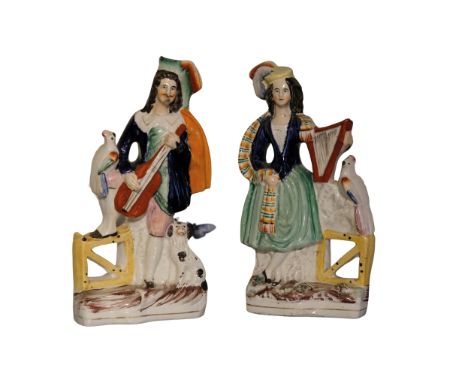 A PAIR OF VICTORIAN STAFFORDSHIRE POTTERY TROUBADOUR FIGURES, the male figure playing a guitar, the female with a harp, paint