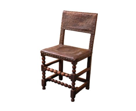 A CHARLES II OAK AND LEATHER UPRIGHT CHAIR, the seat and back with brass close-nailed borders, on bobbin-turned frame, 50cm w