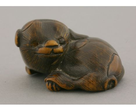A boxwood netsuke, early 19th century, after Masanao, of a puppy curled around and with crossed paws, engraved Masatomo, 4.5c