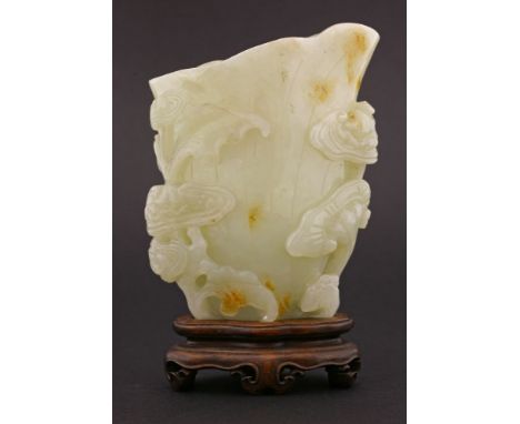 A good jade lotus Libation Pourer,possibly 18th century, the pale green stone suffused with toffee patches and boldly carved 