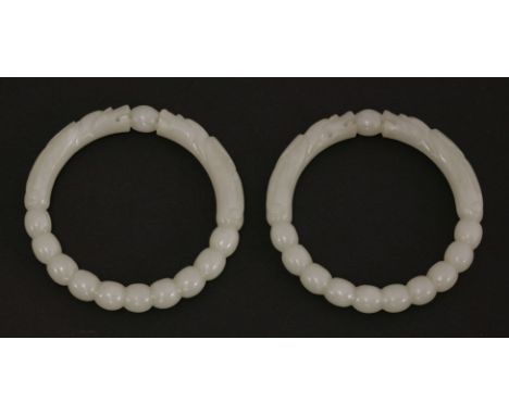 A pair of jade bangles, possibly 19th century, carved with two opposing dragon heads confronted on a pearl, the rest depictin