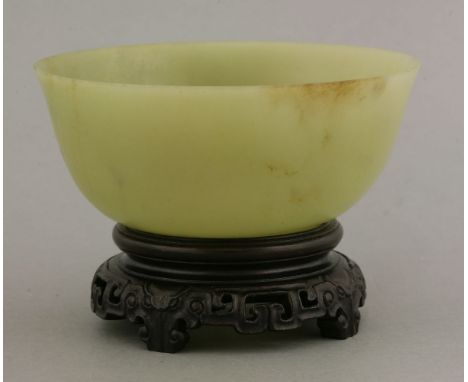 A jade bowl, 20th century, the stone of a grey-green tone, 10.9cm, wood stand (2)