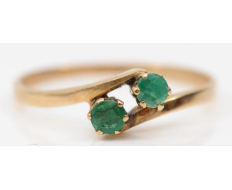 A 9ct gold two stone emerald dress ring, P-Q, 1.2gm. 