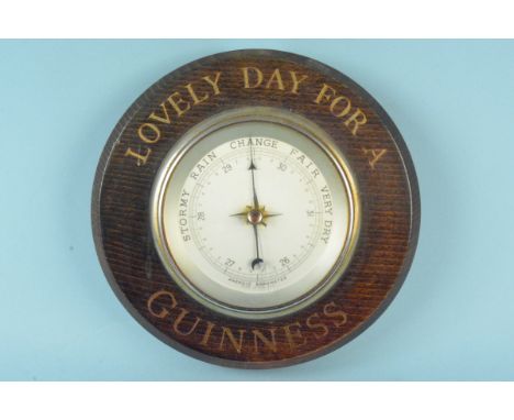 A mid 20th Century oak cased barometer, bears 'Lovely Day for a Guinness', 20.5cm diameter