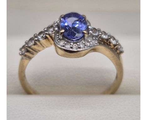 10CT Yellow gold ring fitted with a purple oval cut gem stone, surrounded by white Spinel stones. 2.27grams. Ring size P.