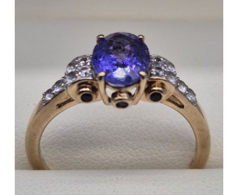 10ct yellow gold ring fitted with an oval cut purple Tourmaline gem stone. Shoulders are fitted with round cut white sapphire