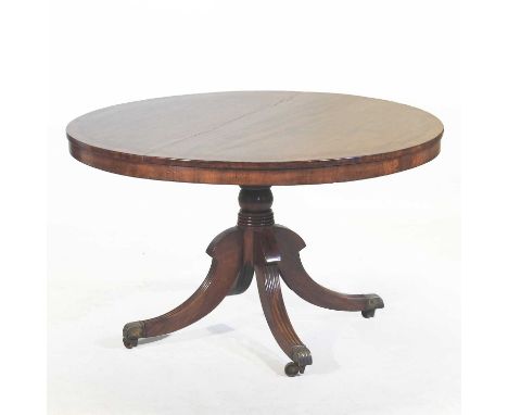 A Regency mahogany breakfast table, having a hinged circular crossbanded top, on a turned column and quadruped base, terminat