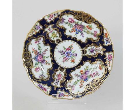 An 18th century Worcester porcelain plate, circa 1770, reserved with floral panels, on a blue scale ground, blue hatched squa