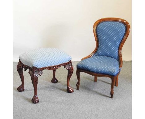 A Victorian style blue upholstered nursing chair, together with a Chippendale style heavily carved mahogany footstool, on cla