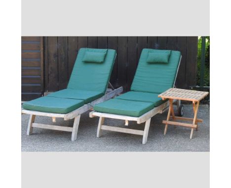 A pair of teak garden loungers, with loose cushions, together with a folding garden table (3)Condition report: Overall solid 