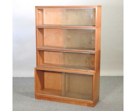 A mid 20th century Minty light oak four tier glazed sectional bookcase, on a plinth base89w x 29d x 134h cm
