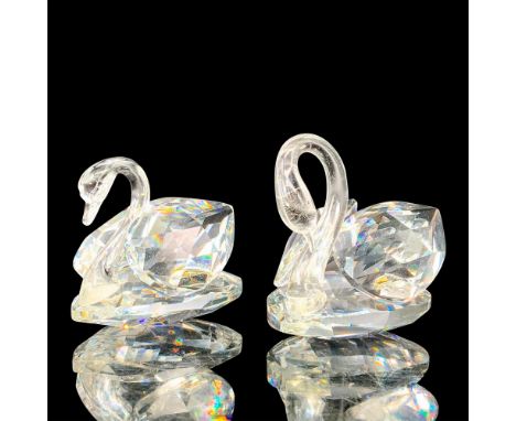 A pair of clear crystal swans that are at rest with their heads faced downwards. Swarovski backstamp. Dimensions of the large