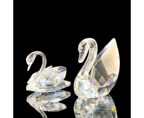 A pair of clear crystal swans that are at rest with their heads faced downwards. Swarovski backstamp. Dimensions of the large