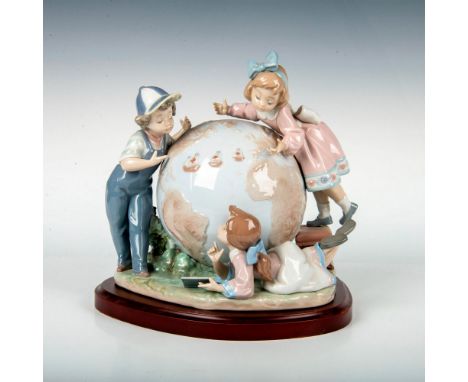 A glazed porcelain figure of three children surrounding a large globe with the three boats from the Columbus voyage on the op