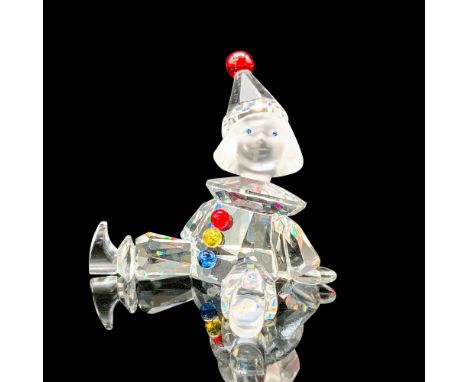 A figure that depicts a clear crystal puppet with a frosted crystal head and red, yellow, and blue crystal used for the acces