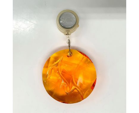 An orange-colored round crystal ornament with a flame symbol carved into the center. Swarovski backstamp. This item has its o