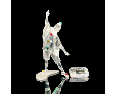 A clear crystal figure of a jester with green, yellow, and red crystal used for his accessories in an arm opened pose along w