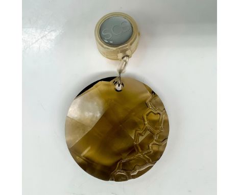 A brown round crystal ornament with lines carved into the side to resemble rocks. Swarovski backstamp. This item has its orig