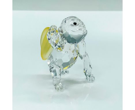A clear crystal figure that depicts a gorilla holding a bunch of yellow crystal bananas behind his back with black crystal be