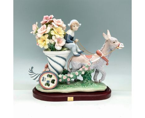 A glossy figurine portraying a youthful driver guiding a cornucopia brimming with flowers, elegantly pulled by a donkey. Rema