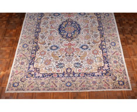 A woven carpet in Kashan style, the cream field decorated with polychrome flowers interspersed with depictions of porcelain v