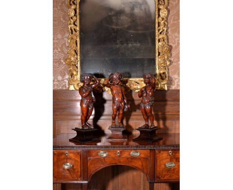 A pair of carved mahogany putti, early 19th century, previously architectural or furniture supports, portrayed standing, one 