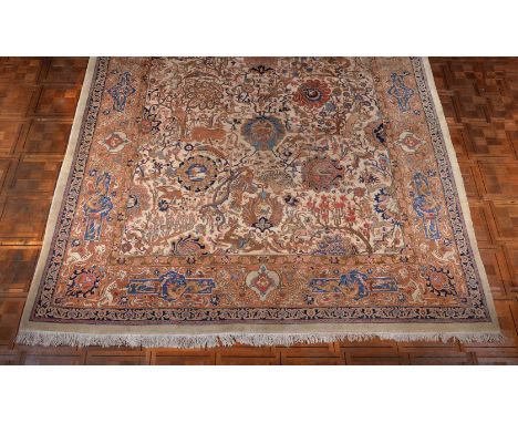 A Tabriz carpet, the cream field decorated with flowering trees and flowerheads interspersed with animals including lions, ti